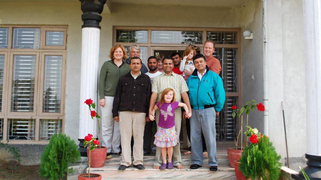 Amy standing on a porch in Nepal, with colleagues and family